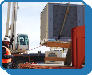 a wide angle of a crane lowering an hvac unit onto the roof of a commercial building